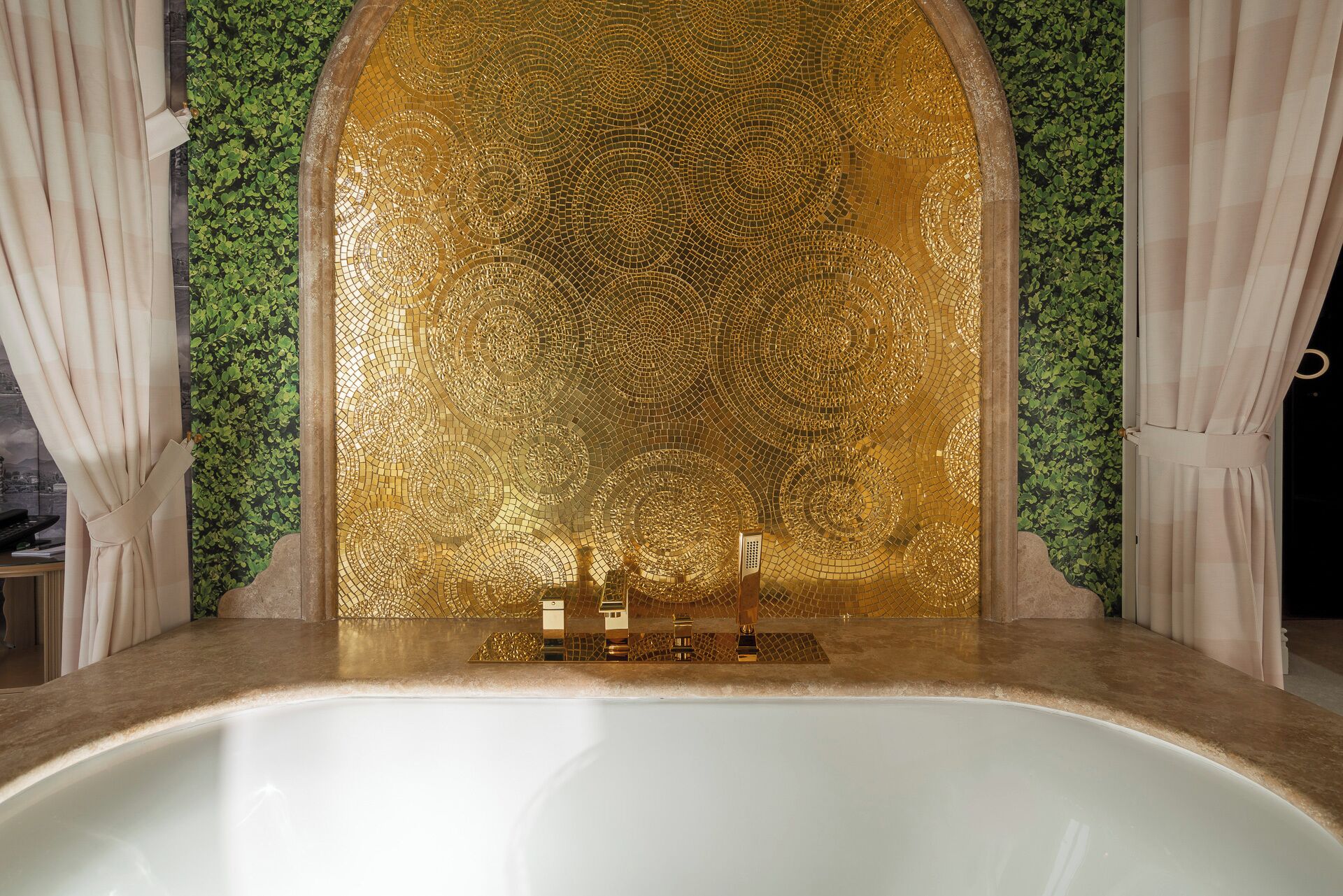 A bathtub with a mosaic wall behind it, a small sink, and a mirror.