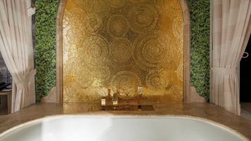A bathtub with a mosaic wall behind it, a small sink, and a mirror.