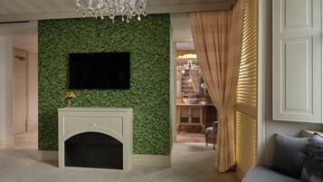 Un salon doté d’une cheminée, d’un téléviseur fixé au mur, d’un lustre et donnant sur un espace salle à manger.