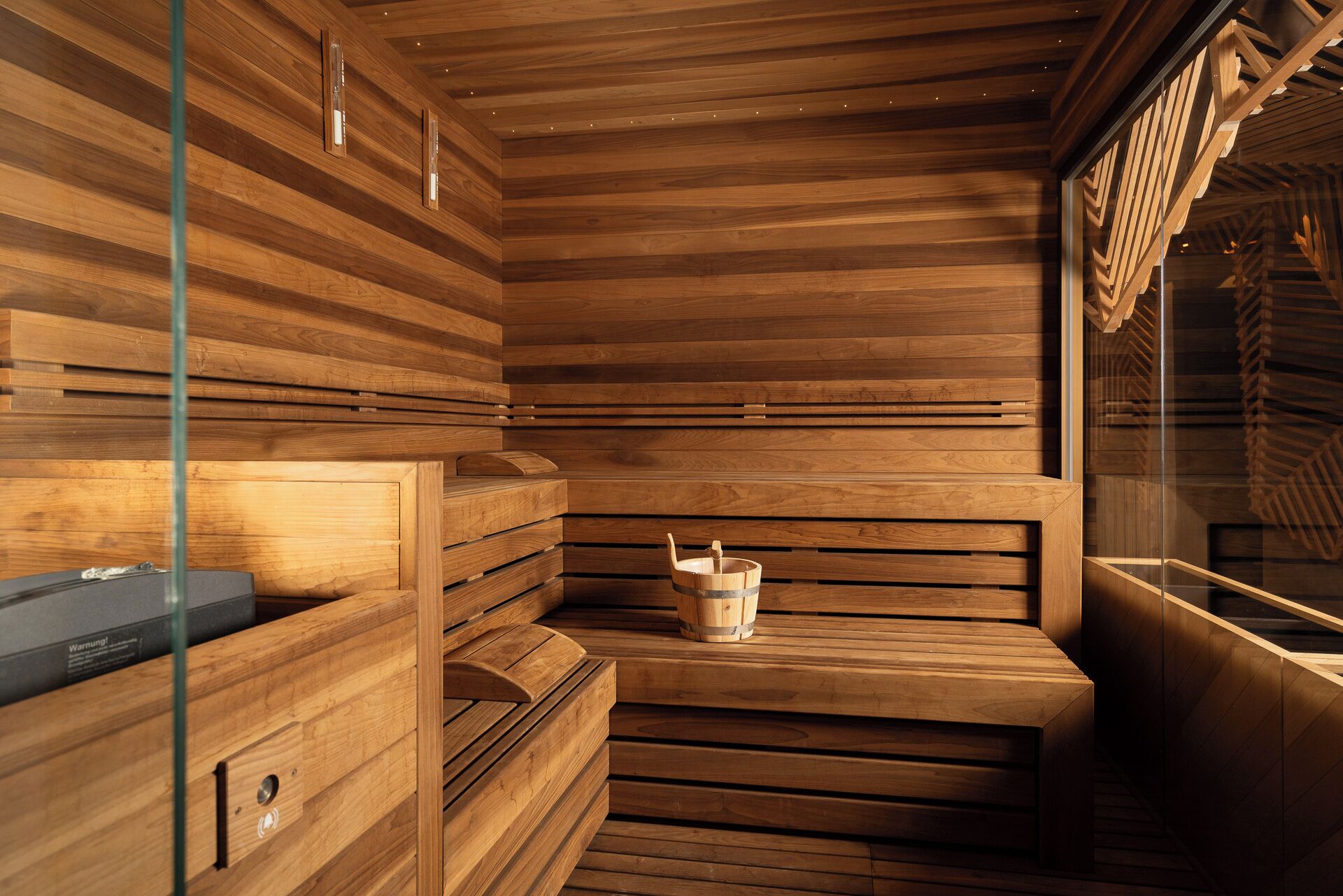Una sauna con panche in legno e un catino di legno.