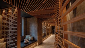 Ein modernes Interieur mit Holzbalkendecke, einer Sitzecke mit Kissen und einer Steinwand.