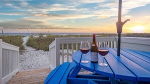 Eine Holzterrasse mit einem Tisch für zwei Personen mit Blick auf einen Strand.