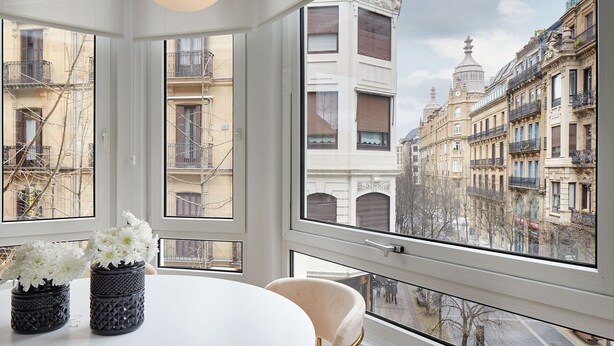 A modern interior with a large window offering a view of historic European buildings. - Getaria by FeelFree Rentals (San Sebastian)