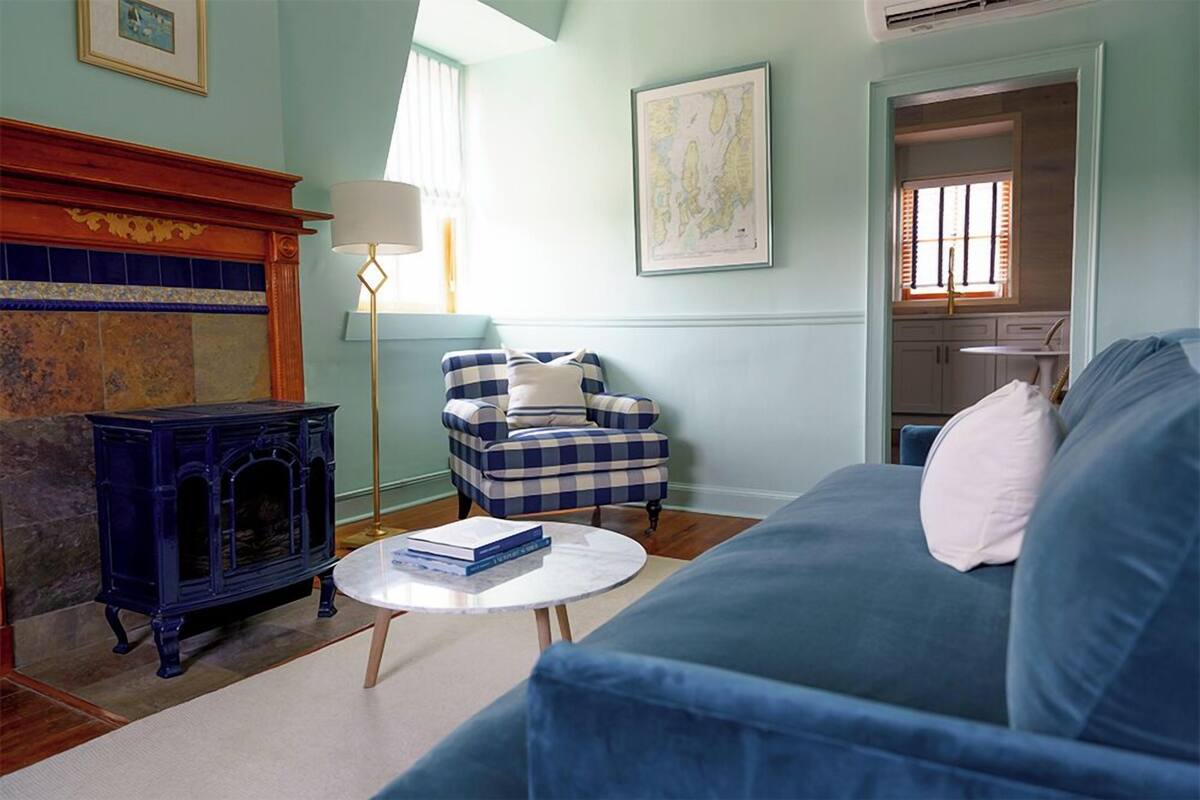 A living room with a blue sofa, a checkered armchair, a blue fireplace, and a round coffee table.