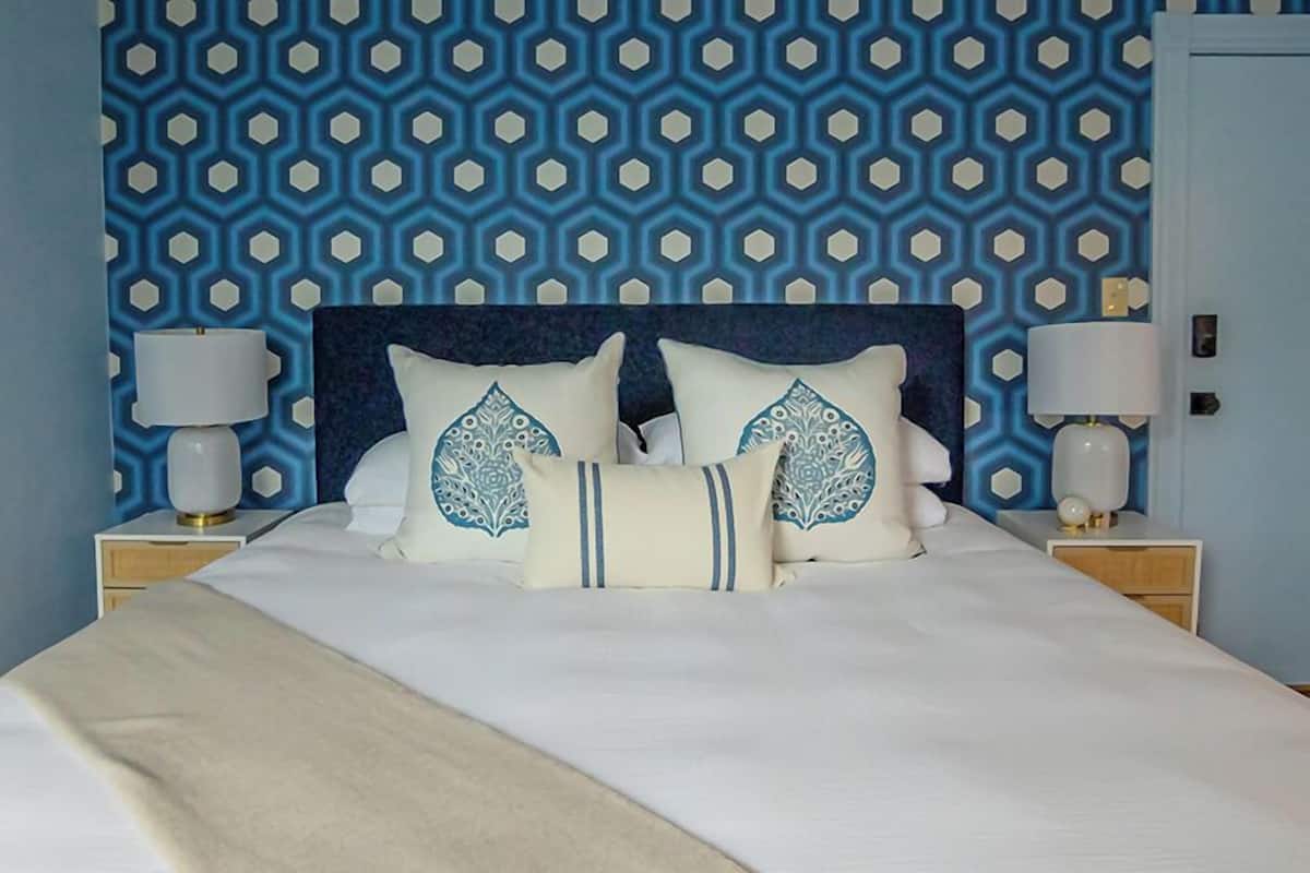 A bed with a dark headboard, two bedside lamps, and decorative pillows with a geometric pattern.