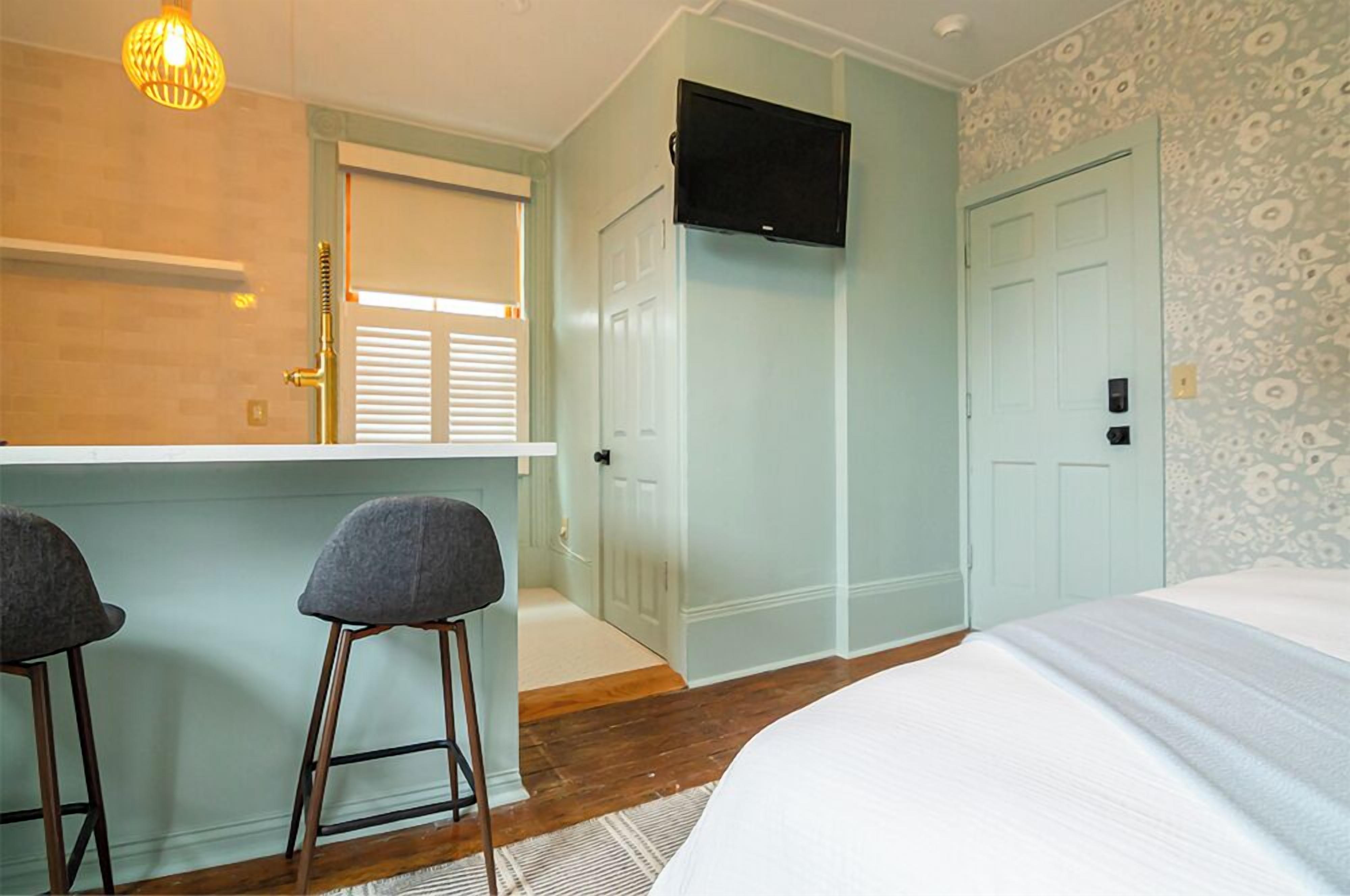 Ein Schlafzimmer mit Bett, einem an der Wand befestigten Fernseher und einem Badezimmer mit Dusche und Toilette.