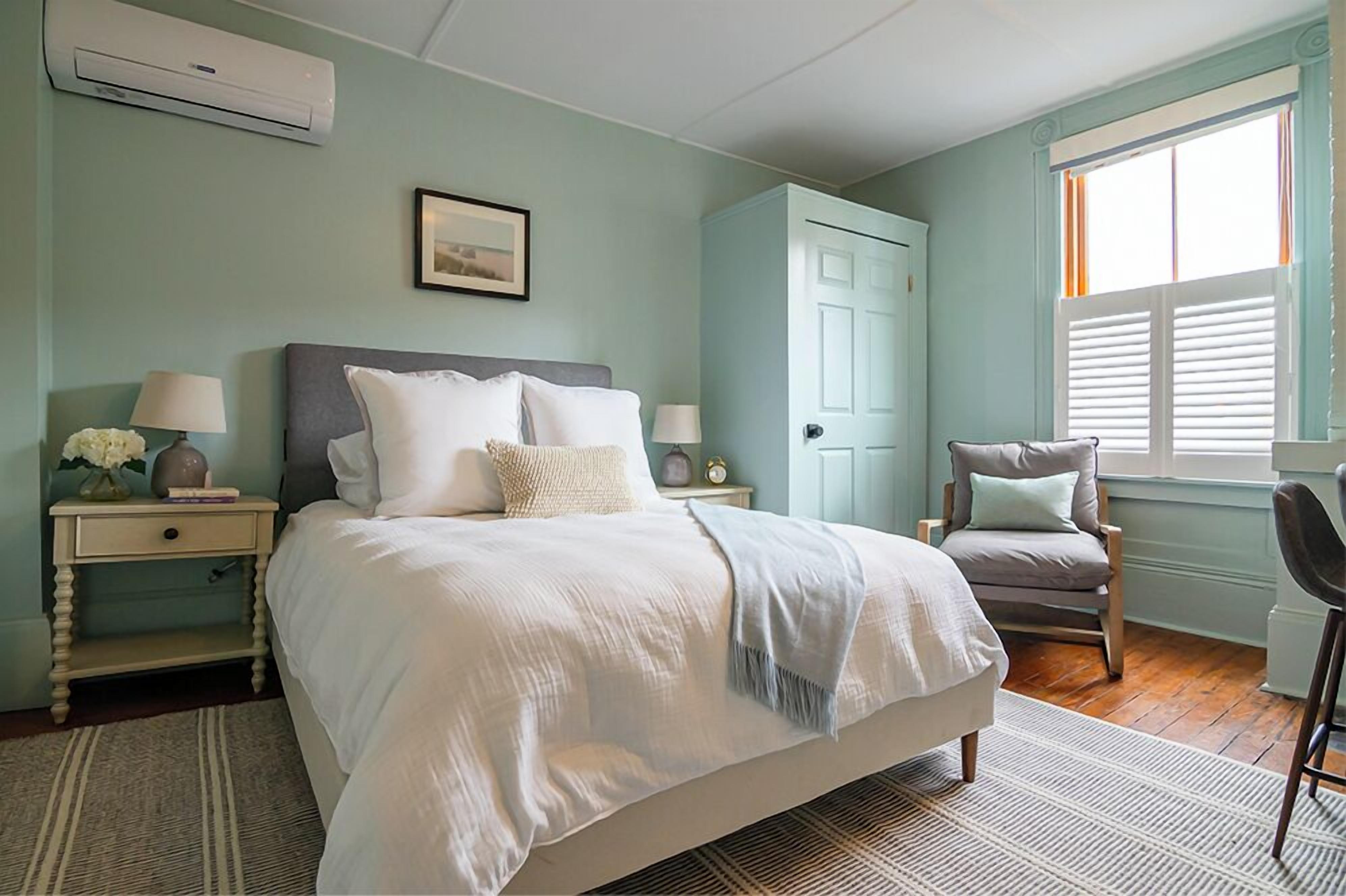 Une chambre à coucher avec un lit, des tables de chevet, une chaise, une porte et une fenêtre.