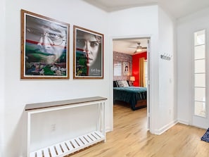 A hallway with a white console table, two framed posters, and a bed with a red wall and a brick pattern in the background. - Single-Level Themed Home with Pool/Spa, By Disney (Kissimmee)