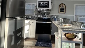 Et moderne køkken med rustfrit stål, en central ø og en dekorativ loftlampe.