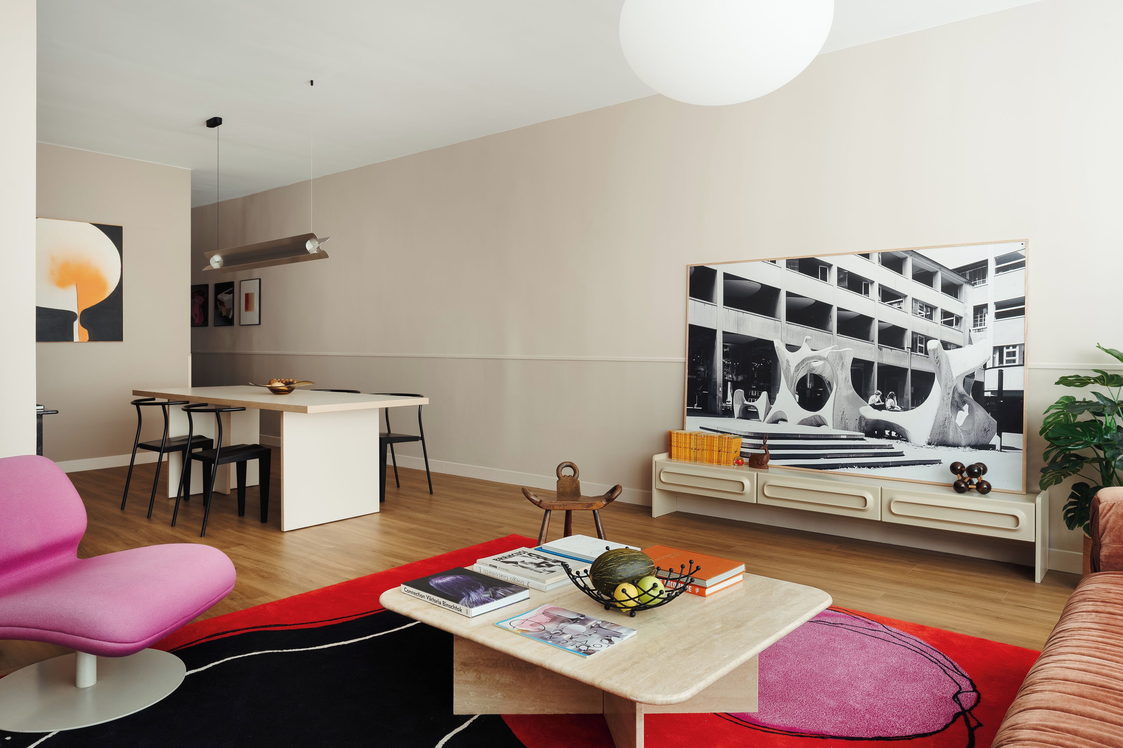 Una sala moderna con comedor, un cuadro abstracto grande y una estantería llena de libros y adornos.