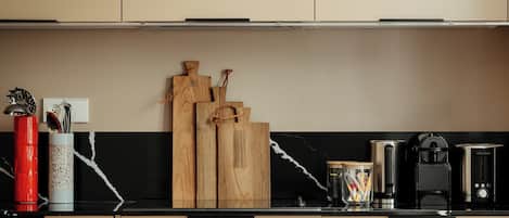 A modern kitchen with a red table and black chairs, a coffee machine, and wooden utensils on the counter.