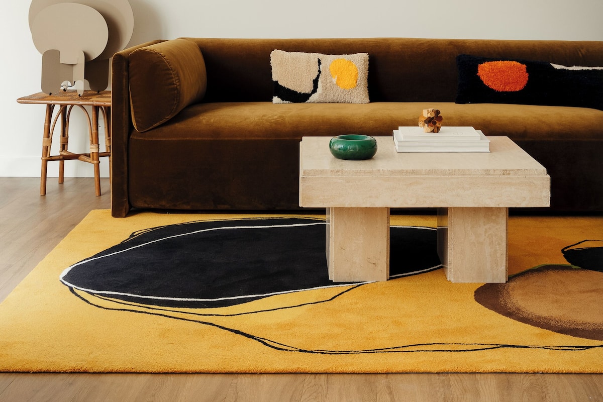 Un salon moderne avec un canapé marron, une table basse en bois et un tapis jaune.