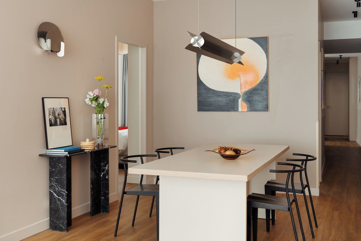 Una cocina moderna con una isla central, sillas negras y una mesa de comedor.