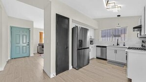 A modern kitchen with white cabinets, stainless steel appliances, and a wooden floor. - Vegas Jackpot: With Pool & Spa (North Las Vegas)