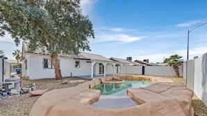 A backyard with a swimming pool, a tree, and a house. - Vegas Jackpot: With Pool & Spa (North Las Vegas)