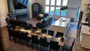 A modern living room with a fireplace, a dining area, and a kitchen. - Big Wolf Barn: Where Big Groups Have Big Fun, Lakegfront in Jackson, MI. (Jackson)