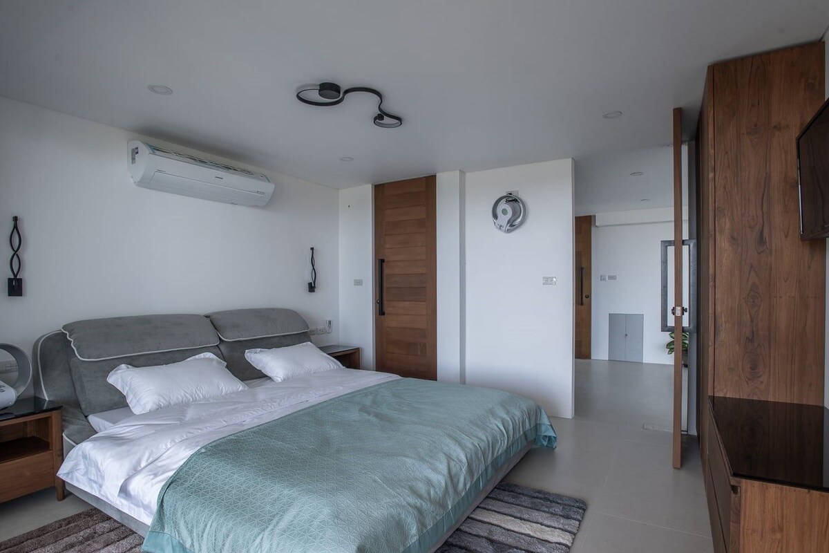 Un dormitorio moderno con una cama grande, un armario de madera y televisión integrada.