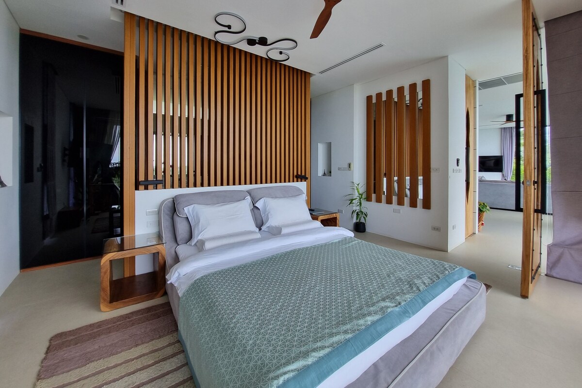 Un dormitorio moderno con una cama grande, listones de madera en la pared y un ventilador de techo.