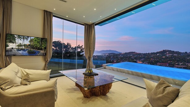 A modern living room with a glass coffee table, beige sofas, and a large TV. - Magic Suites (Koh Samui)