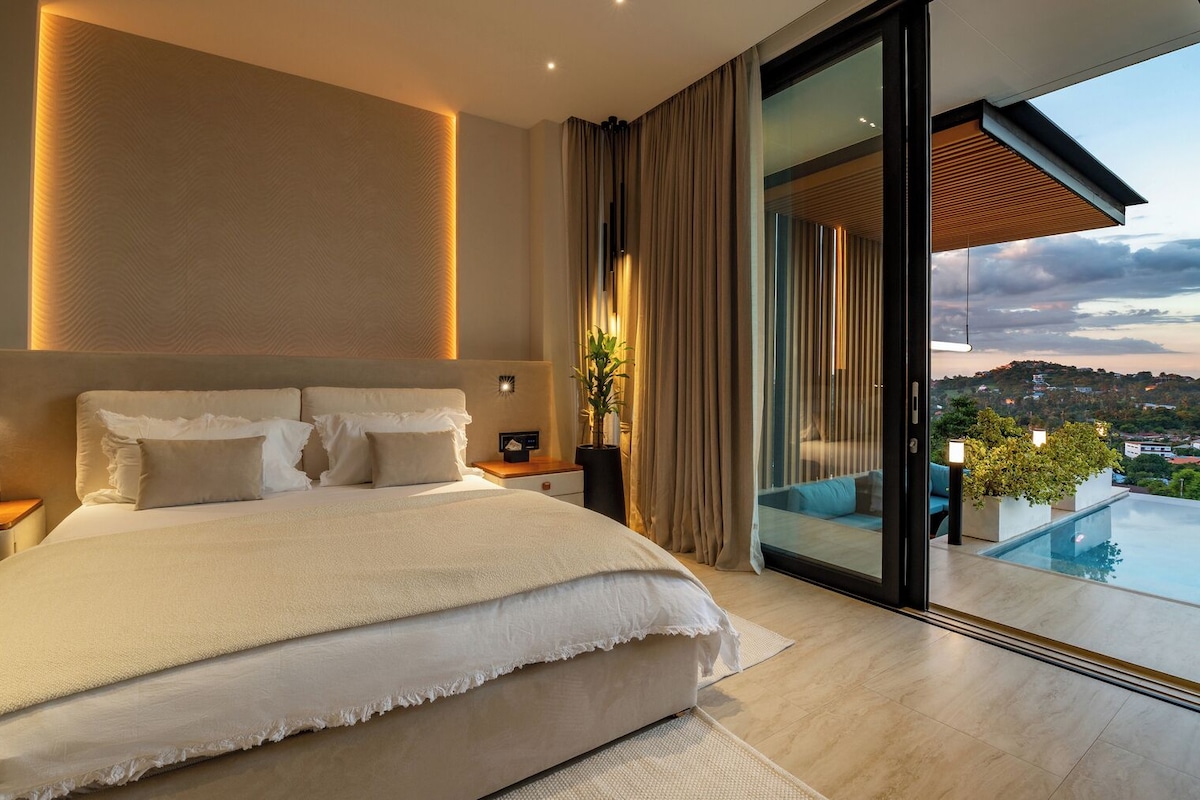 A modern bedroom with a large bed, a nightstand, a bedside table, a potted plant, and a view of a pool and landscape.