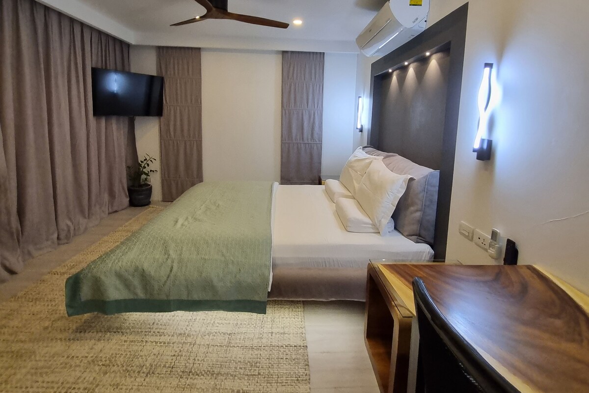 Un dormitorio moderno con cama, escritorio, ventilador de techo y aire acondicionado.
