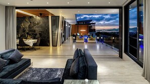 A modern interior with a dining area, sofas, and a balcony with a view. - Magic Suites (Koh Samui)