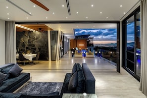 A modern interior with a dining area, sofas, and a balcony with a view.