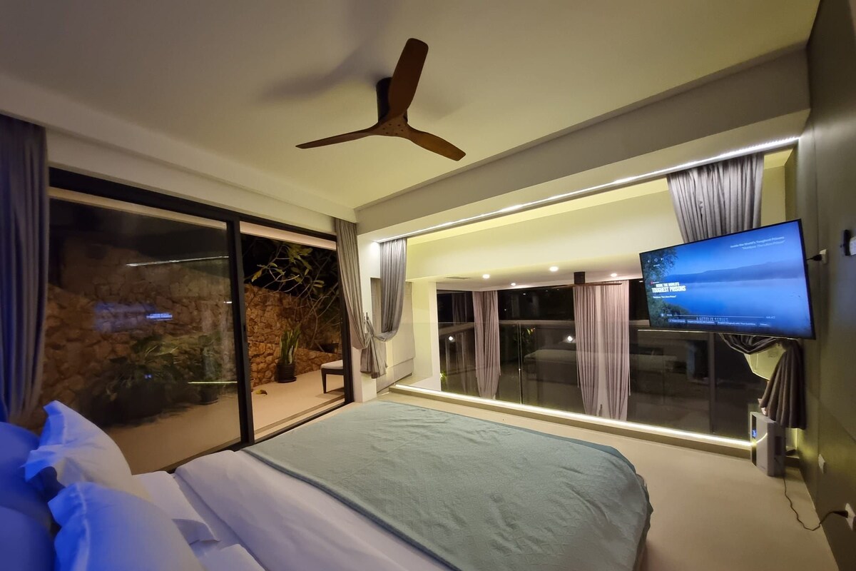 A modern hotel room with a large bed, a television, and a balcony with a view.
