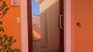 Une entrée moderne avec une porte en verre, un petit espace jardin et une enseigne indiquant le nom de la propriété.