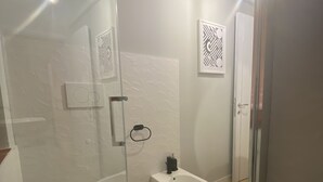 Une salle de bain moderne équipée de toilettes, d’un bidet et d’une douche à parois de verre.