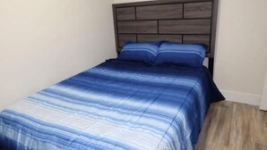 A bedroom with a bed, a headboard, and a wooden floor.