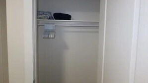 A closed white closet with a hanging rod and a folded towel.