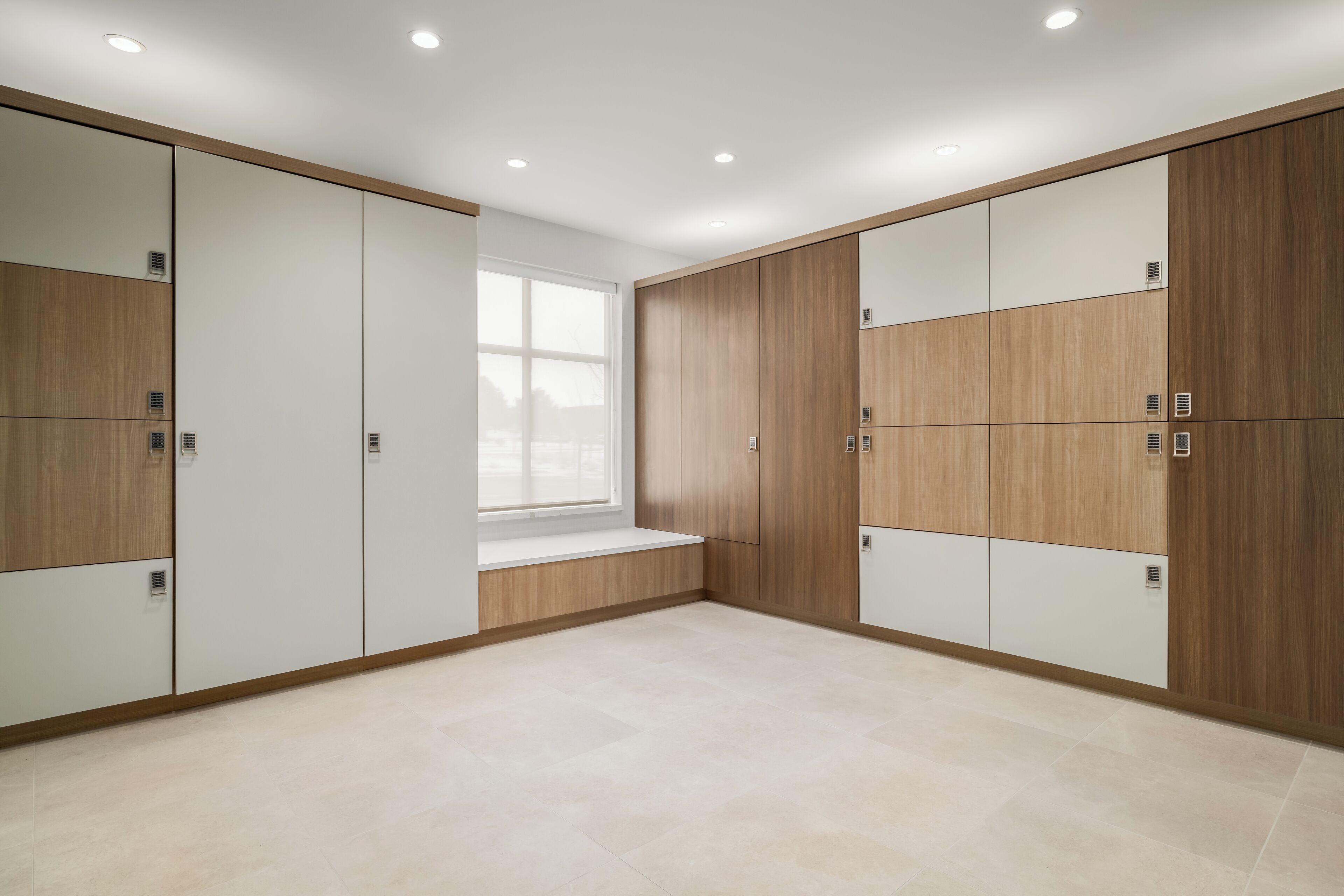 A modern room with built-in wardrobes, a large window, and a bench.