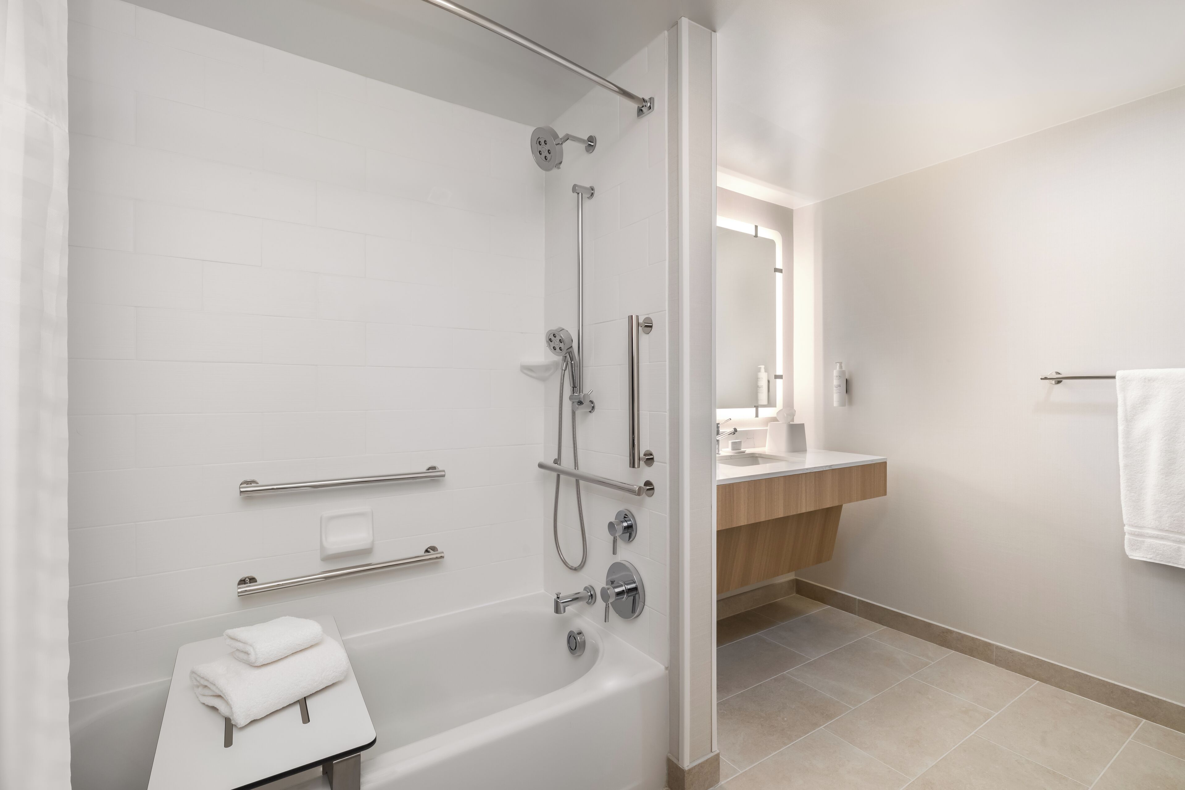 A modern bathroom with a bathtub, shower, and vanity.