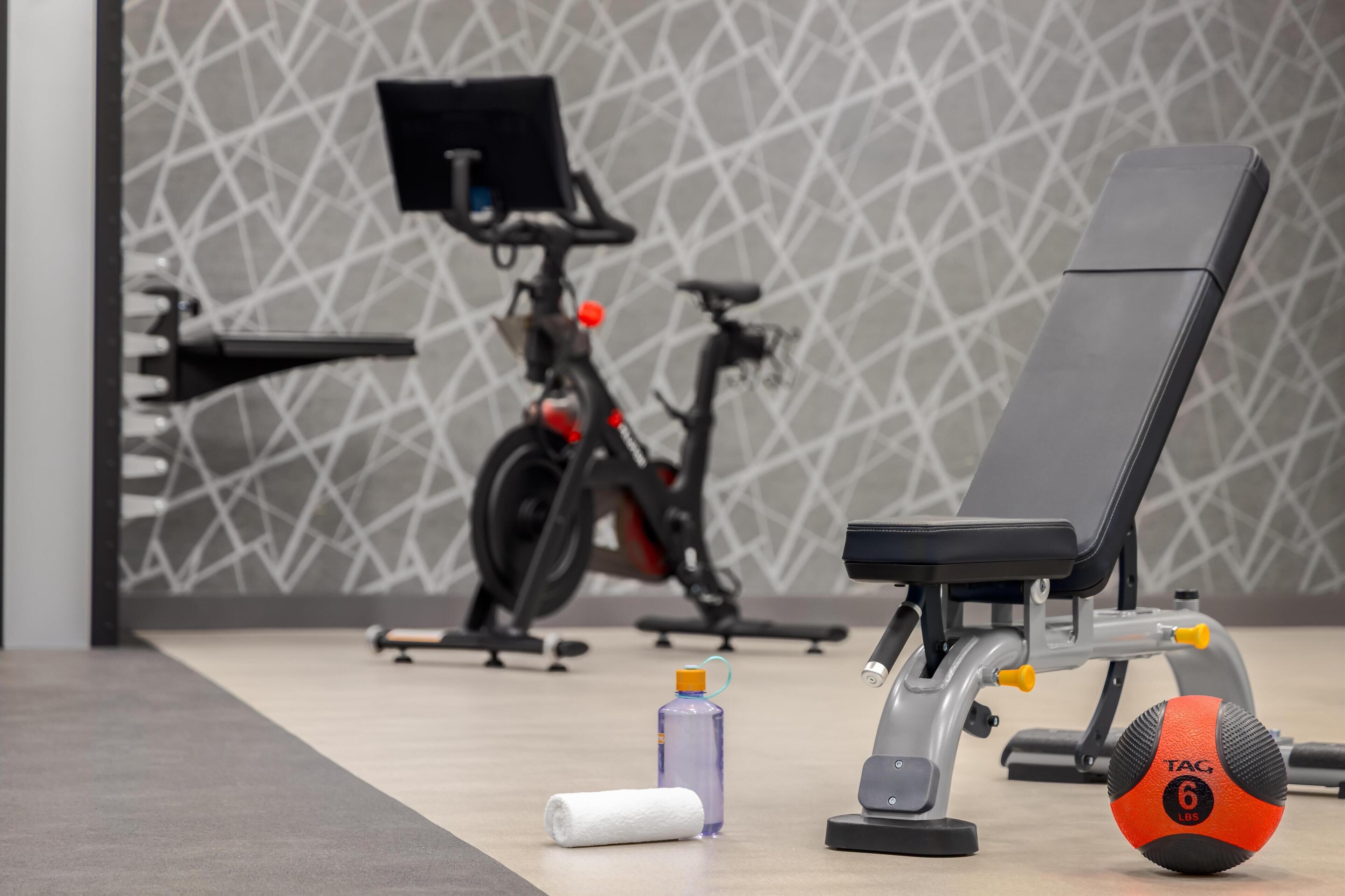 A gym with a stationary bike, a bench, and a weight plate.
