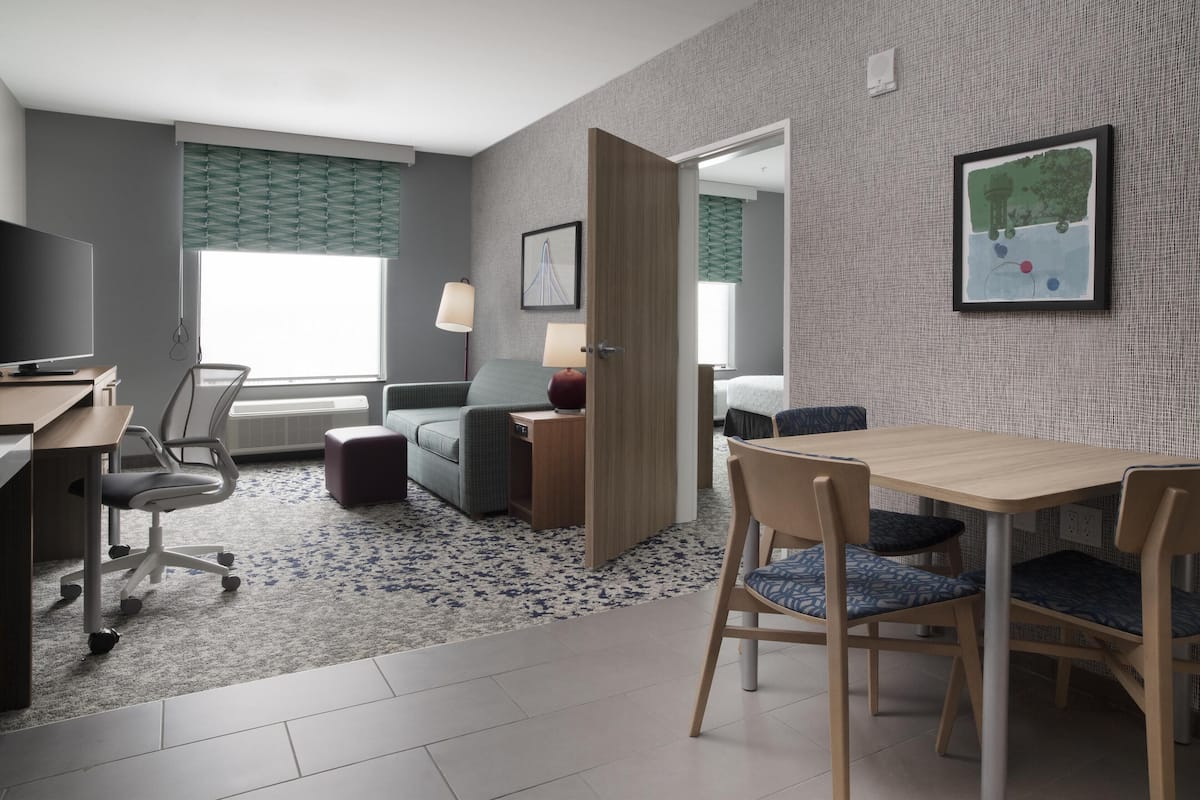 Une chambre d’hôtel équipée d’un bureau, d’une chaise, d’un canapé et d’une table à manger avec des chaises.
