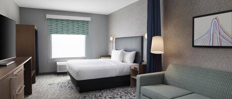 A hotel room with a bed, a desk, a chair, a TV, a window with curtains, and a wall-mounted lamp.