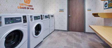 A laundry room with multiple washing machines, a wooden door, and a sign on the wall.