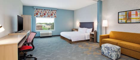Hotelkamer met een bed, een slaapbank, een bureau met stoel, een televisie en een raam met uitzicht op gebouwen.