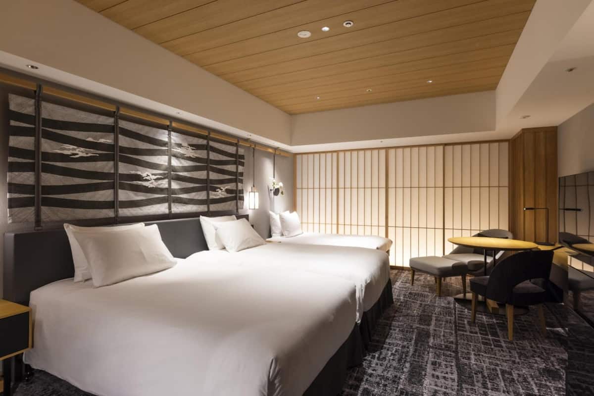 A modern hotel room with a large bed, a desk, and a seating area.