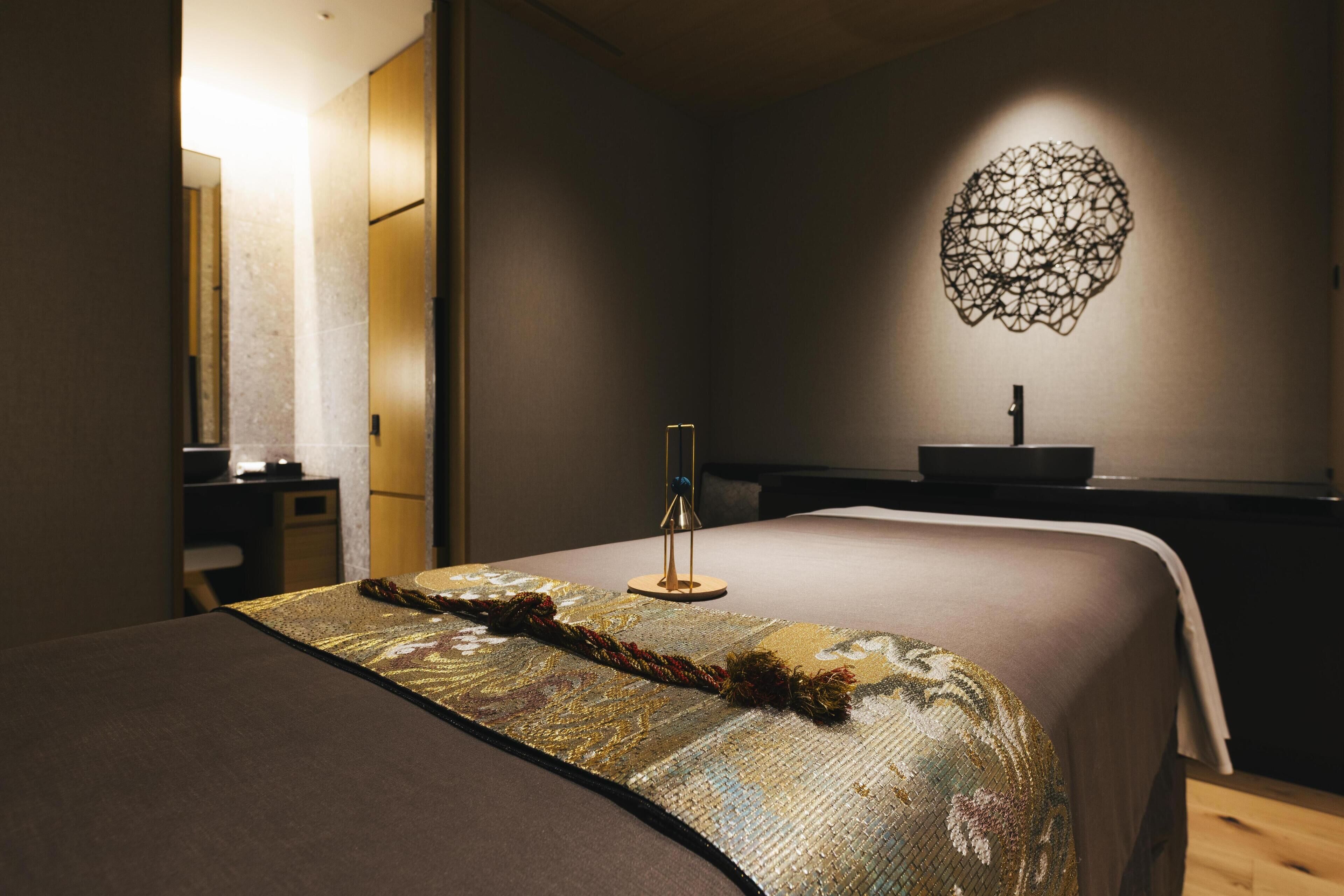 A hotel room with a bed, a bedside table, a lamp, and a wall-mounted artwork.