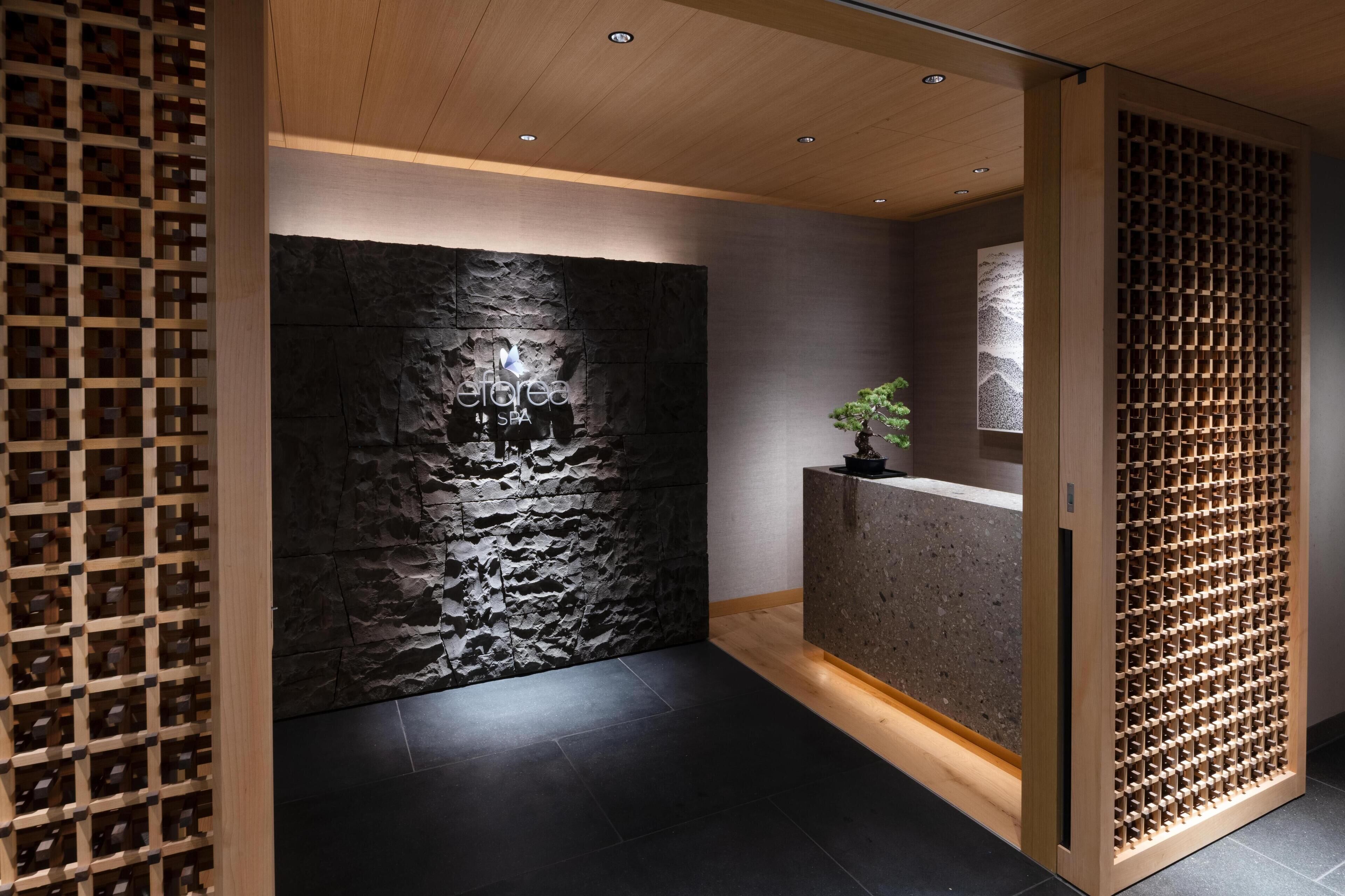 A reception area with a stone wall, wooden reception desk, and a plant.