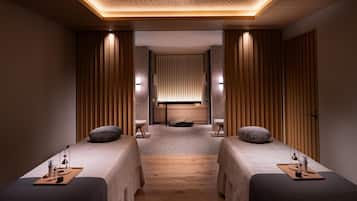 A spa room with two beds, a massage table, and a wooden ceiling.