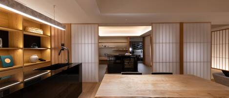 A modern kitchen with wooden cabinetry, a black countertop, and a wooden dining table.