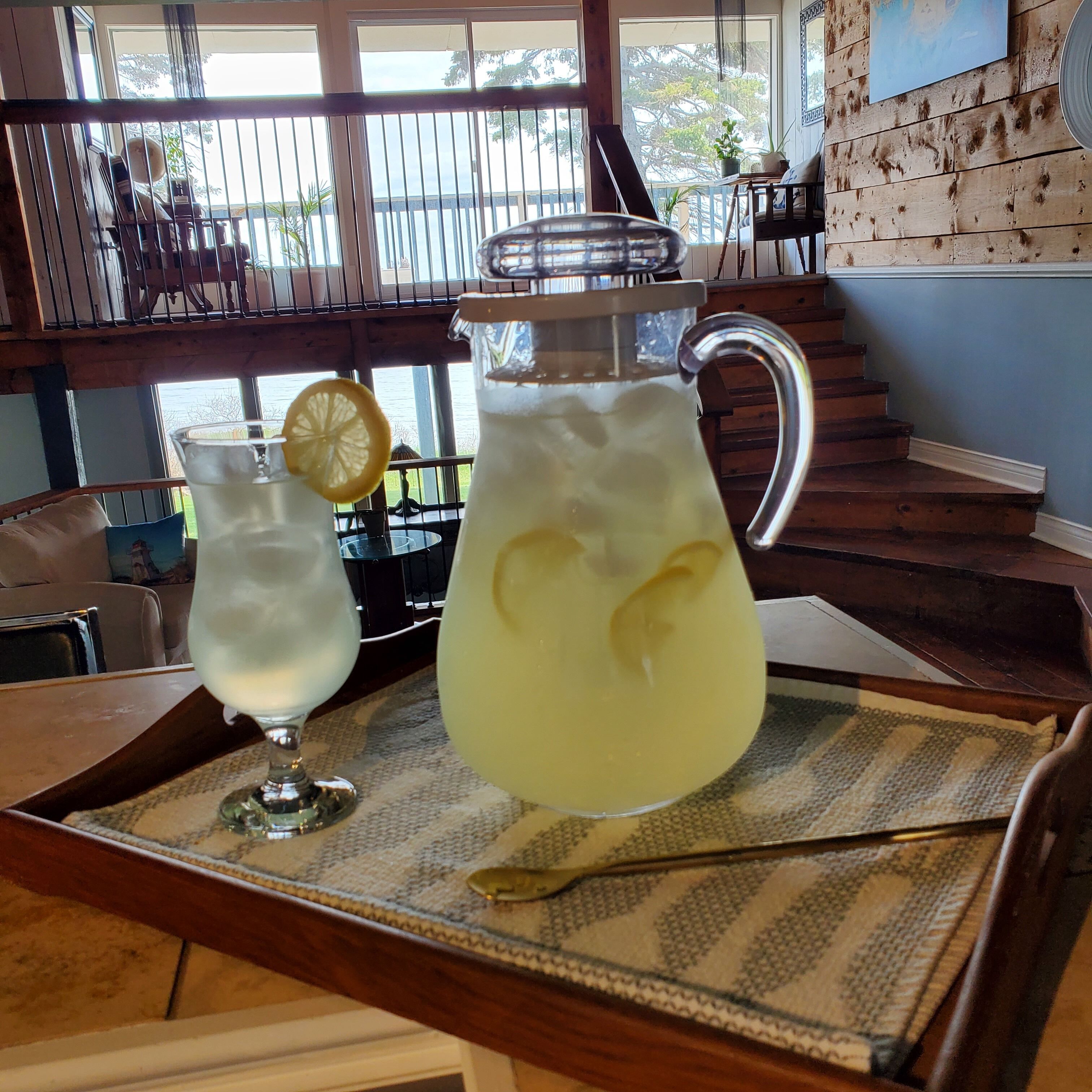 A tray with two glasses of a light-colored beverage, one with a lemon slice, on a patterned mat.