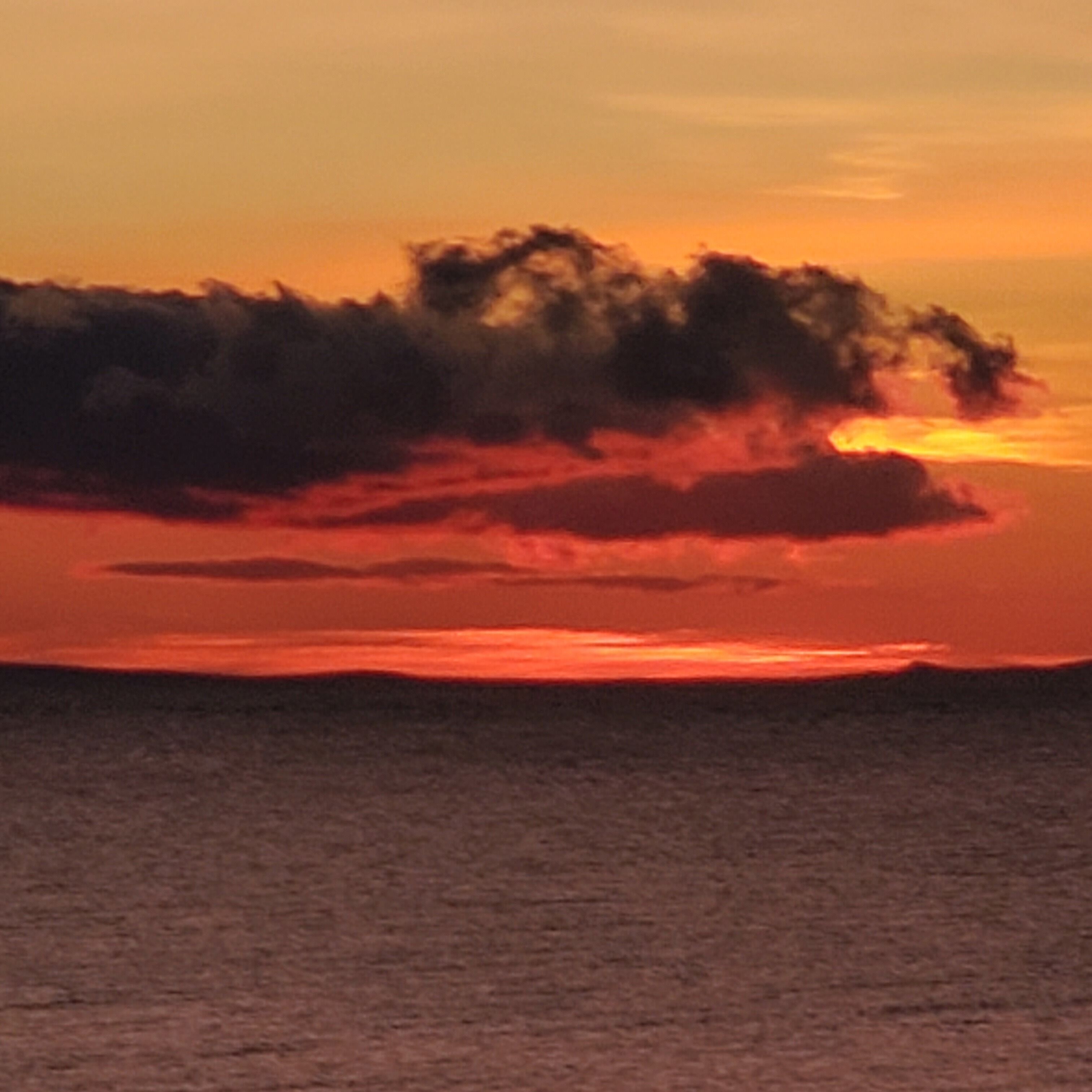 A sunset over a body of water with clouds in the sky.