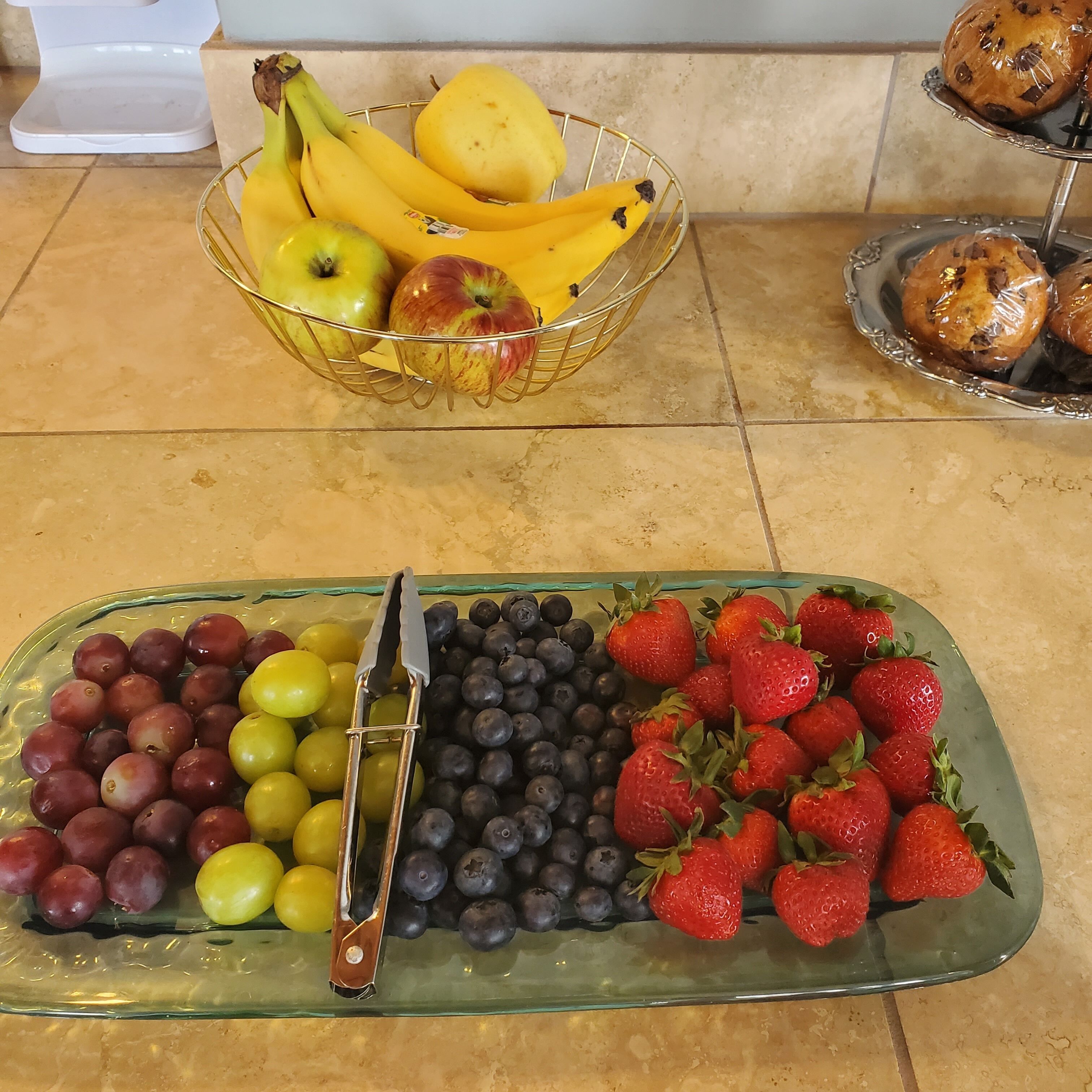 A fruit display with bananas, apples, grapes, blueberries, and strawberries.