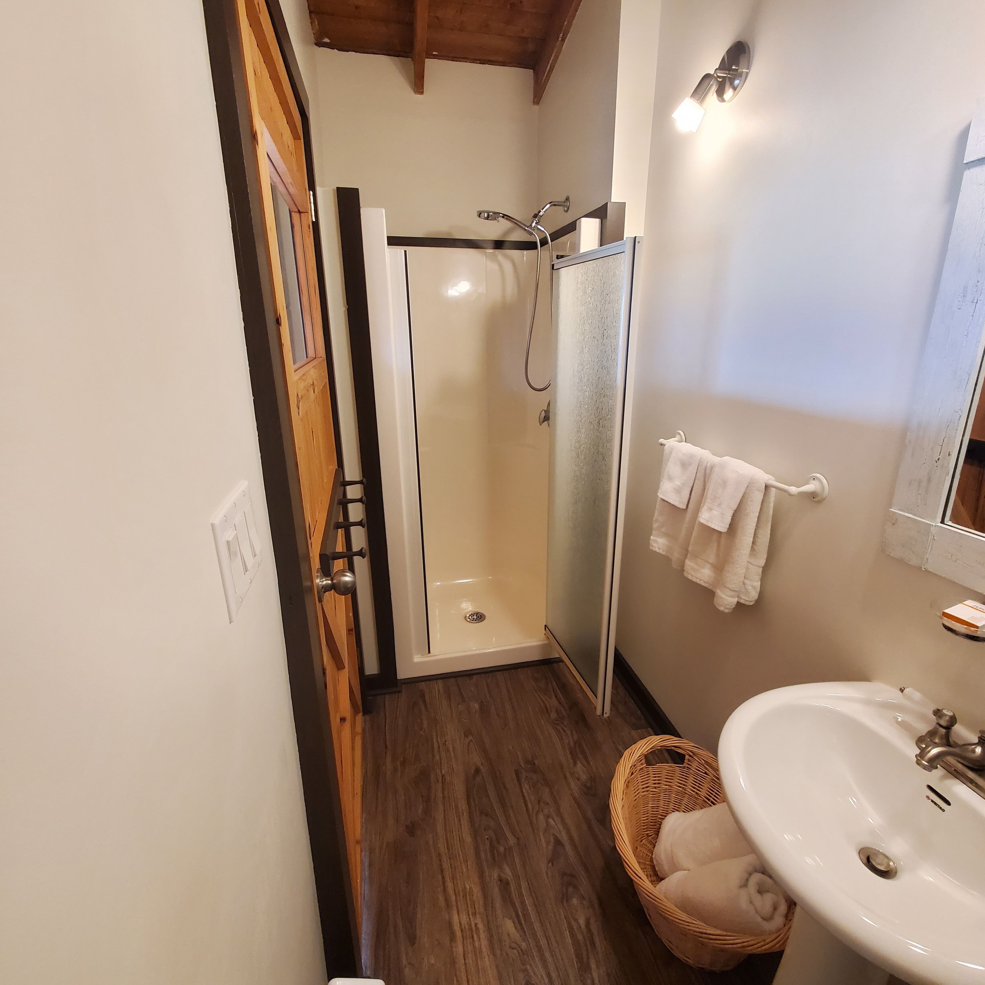 Un baño con ducha, lavamanos y espejo.