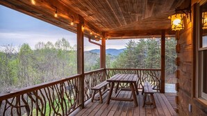 Eine Holzterrasse mit Picknicktisch und Bänken mit Blick auf eine bewaldete Landschaft.