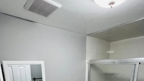 Pieni kylpyhuone, jossa on valkoinen pesuallas, wc ja lasinen suihkuseinä.